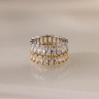 The Colette Eternity Ring in Silver features two rows of clear baguette diamonds on a neutral reflective surface—a striking statement jewelry piece.