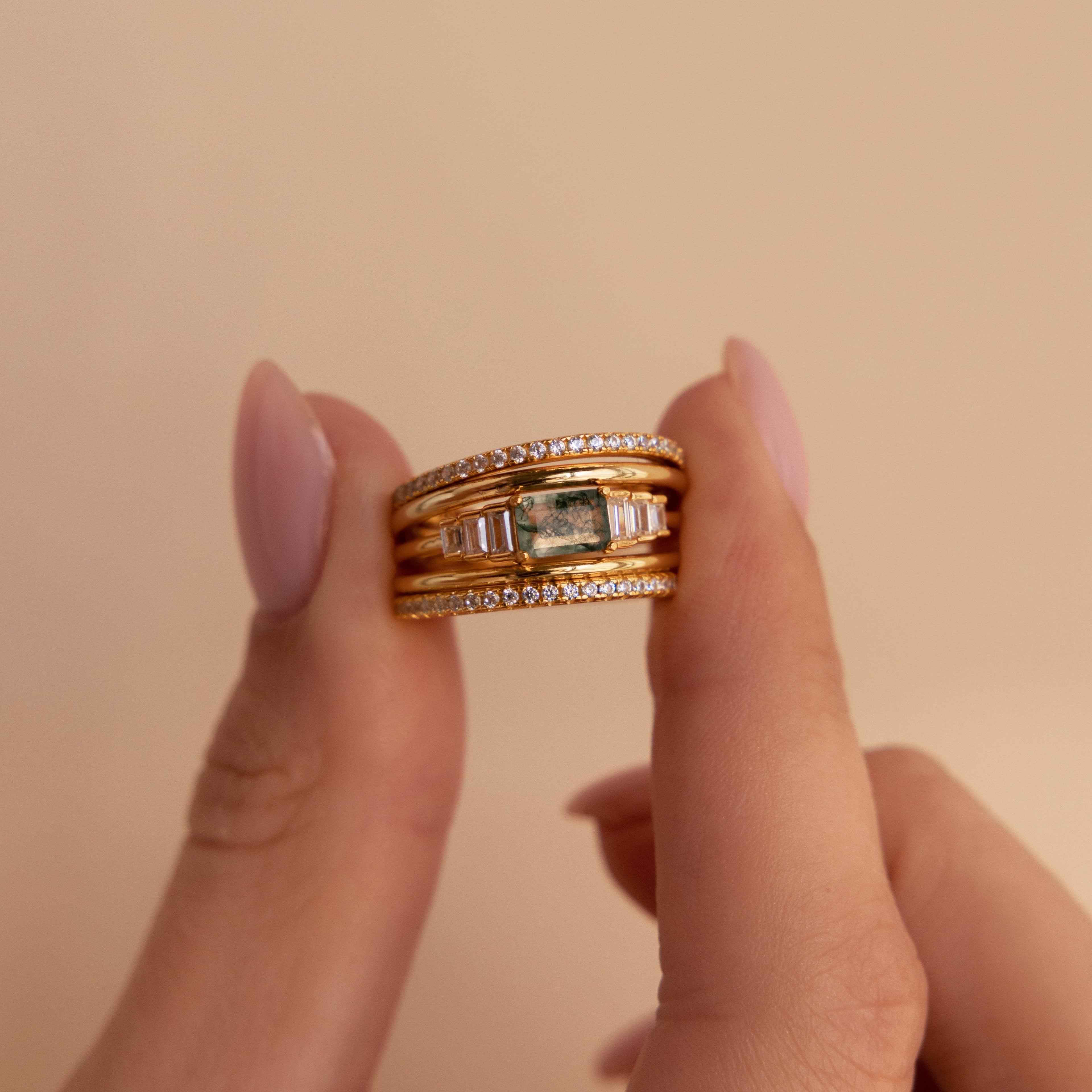 Two hands hold the Agate Diamond Rings Set, featuring sparkling diamonds and a rectangular agate stone, against a beige background—showcasing this stunning vintage-inspired jewelry piece.