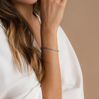 A woman wears the Blue Diamond Tennis Bracelet on her wrist with a white blouse, set against a neutral background.