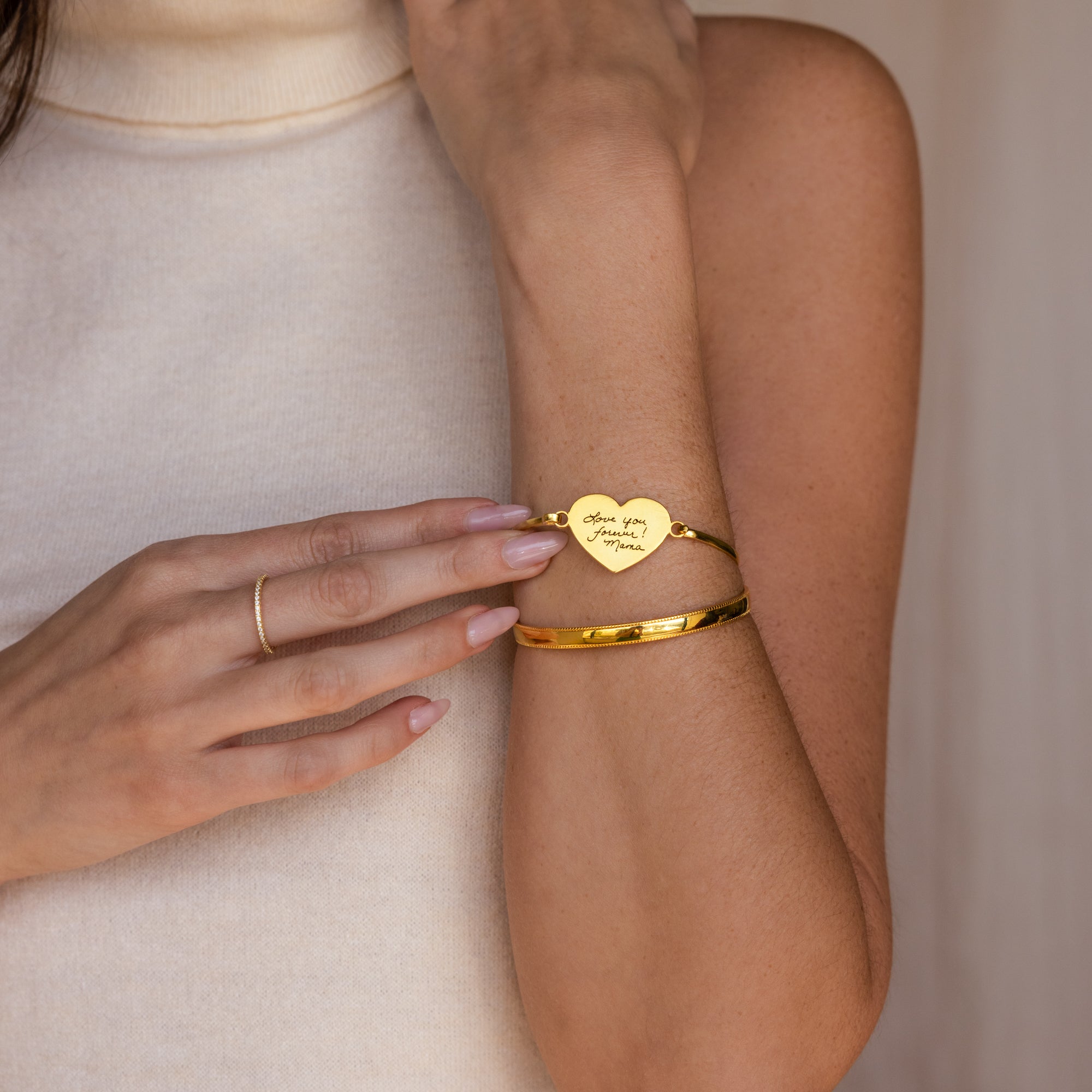 A woman wears the Fingerprint Heart Bangle, featuring a heart-shaped charm engraved with "Love you, Always & Forever," for truly personalized jewelry.