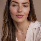 Woman with long brown hair wears a cream blouse and the Pink Opal Butterfly Necklace in Silver, against a neutral background.