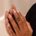 Close-up of manicured hands wearing multiple gold rings with dark gemstones, featuring the Black Diamond Rings Set—a perfect example of stylish jewelry layering.