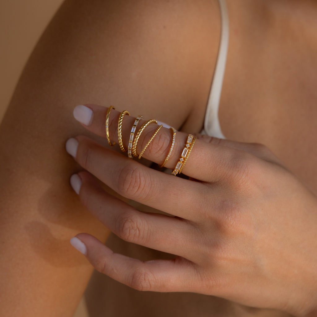 A hand with white nails wears the Diamond Stacking Ring Set on a bare shoulder—a sparkling gold accessory and perfect Christmas gift idea.