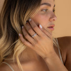 Woman with blonde hair touches her face, showcasing the Diamond Stacking Ring Set in Sterling Silver against a beige background—a stylish and elegant choice, perfect as a thoughtful Christmas gift.