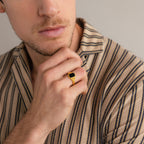 A man in a striped shirt touches his chin, highlighting the Vintage Black Signet Ring on his finger.