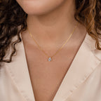 A woman wears the Ophelia Birthstone Necklace, featuring a minimalist gold teardrop pendant, over a cream-colored blouse.