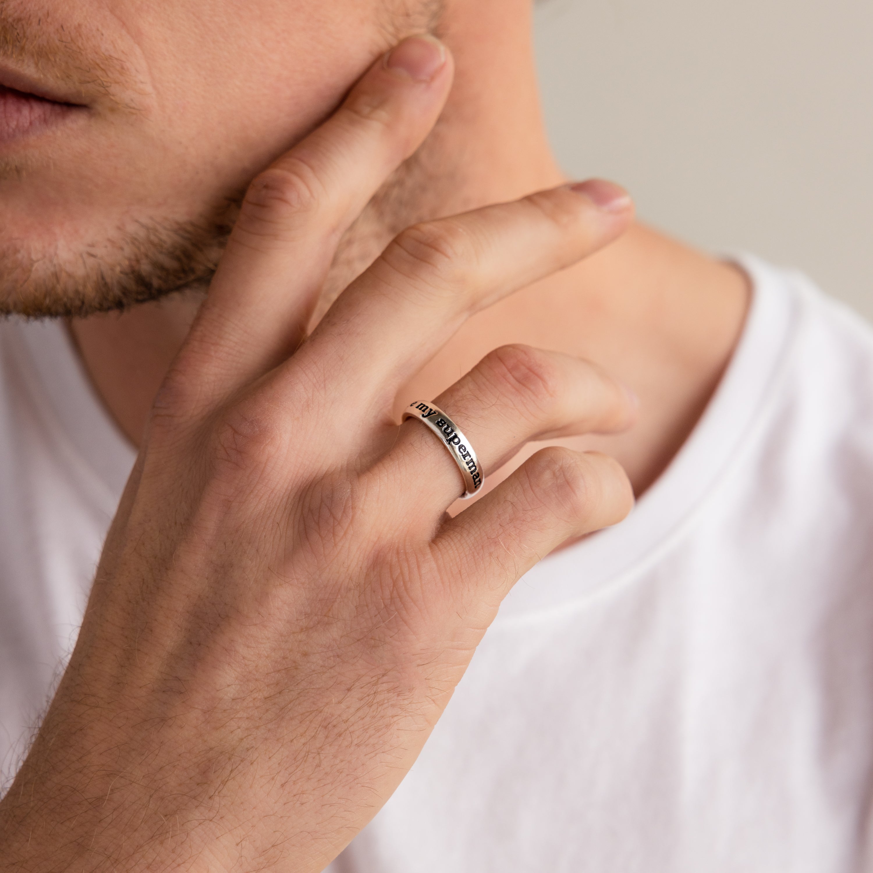 A man in a white shirt touches his face, wearing the stylish Half Round Fingerprint Ring on his finger.
