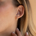 Close-up of a woman's ear adorned with Inside Out Diamond Huggies, her hand gently touching her neck.