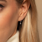 Close-up of a woman's ear wearing the Molly Pearl Huggies in Sterling Silver, featuring a small silver hoop with a dangling pearl.