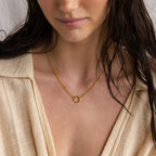 Woman wearing a beige top and the Rolo Circle Charm Necklace in 18K Gold with a small circular pendant, shown from the shoulders up—a perfect minimalist necklace look.