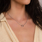 A woman in a cream-colored top wears the Rolo Circle Charm Necklace in Sterling Silver, featuring a customizable circular pendant on a silver Rolo Link Chain.