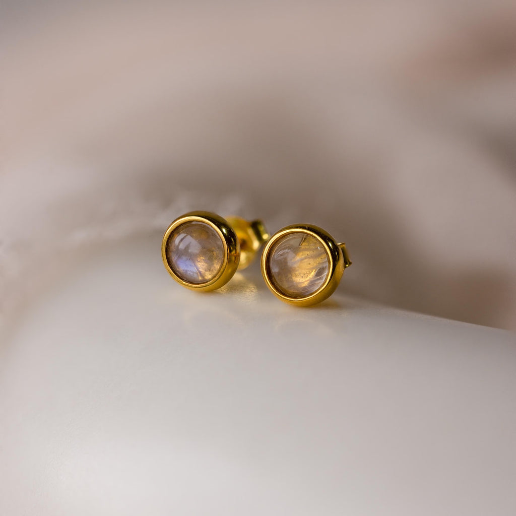 The Moonstone Bezel Studs feature round, translucent moonstones in a gold setting, offering an ethereal touch and understated elegance—perfect for minimalist jewelry lovers.