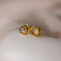 The Moonstone Bezel Studs feature round, translucent moonstones in a gold setting, offering an ethereal touch and understated elegance—perfect for minimalist jewelry lovers.