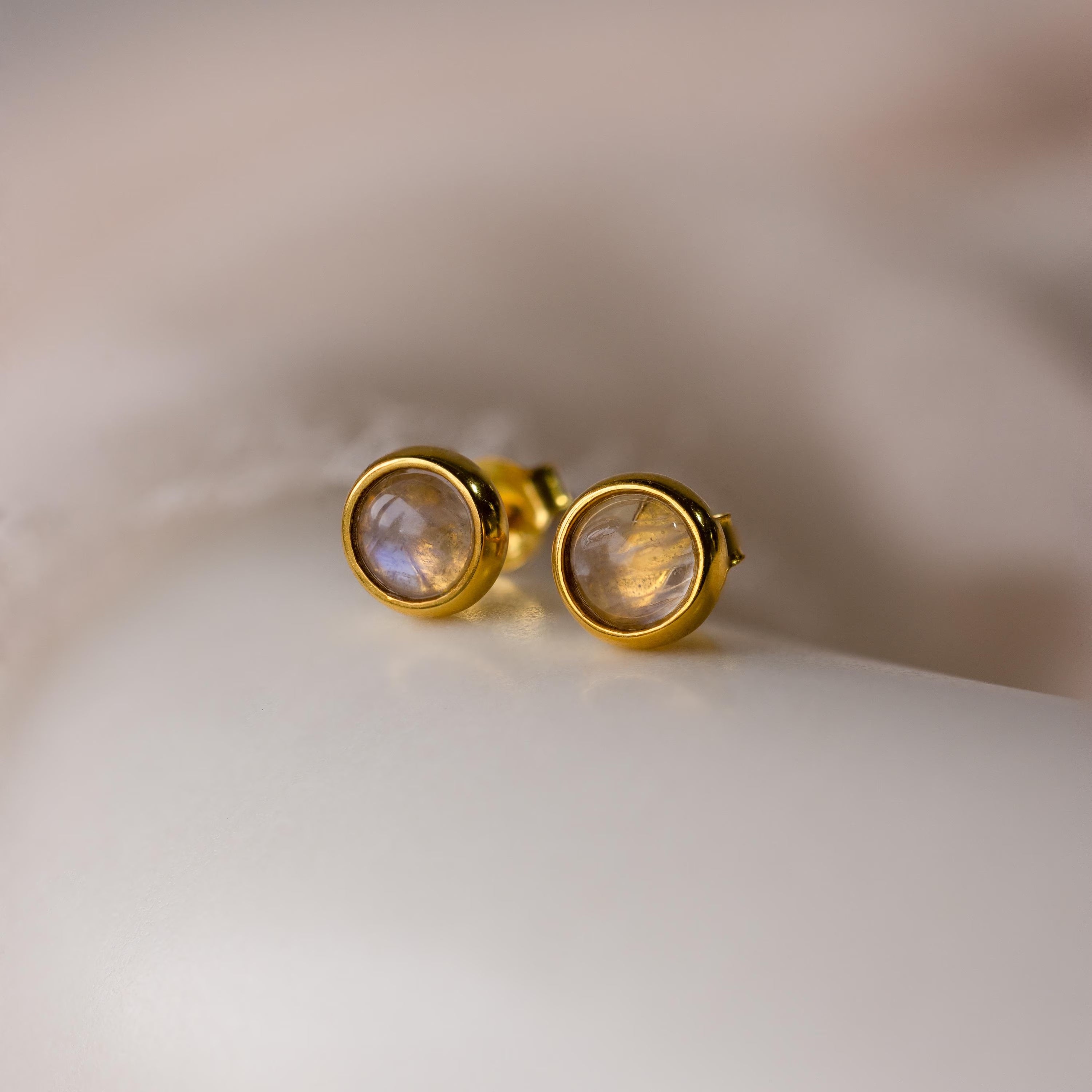 The Moonstone Bezel Studs feature round, translucent moonstones in a gold setting, offering an ethereal touch and understated elegance—perfect for minimalist jewelry lovers.