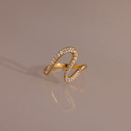 Pave Wave Ring featuring a wavy, abstract gold design encrusted with small diamonds, ideal for stacking and beautifully set against a neutral background.