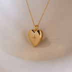 A gold heart-shaped locket with a north star CZ diamond in the center on a delicate cable chain.