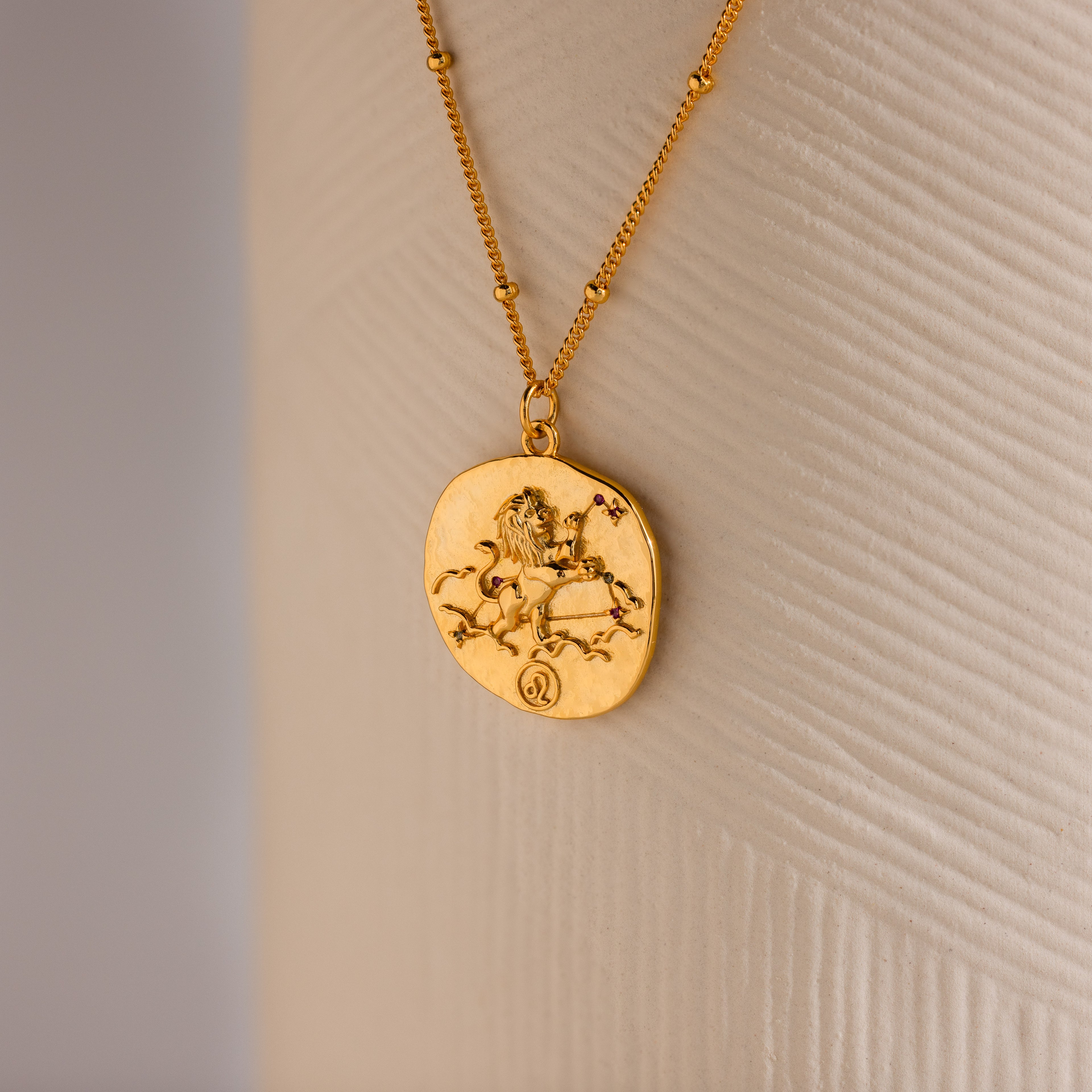 Close up of a Gold 3D Leo Zodiac Coin Pendant Necklace with small CZ gemstones, attached to a dainty satellite chain.
