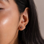 Close-up of a person's ear wearing a Teardrop Birthstone Flatback Stud—an elegant blue gemstone earring that adds a touch of sophistication.