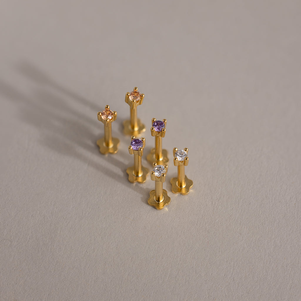 Six Dainty Birthstone Flatback Studs with colorful gemstones are displayed on a light gray surface—a timeless choice, perfect for stacking and multiple piercings.