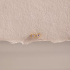 Dainty Pink Tourmaline Flatback Studs with delicate pink stones set in gold, ideal for multiple piercings, shown on a textured beige background.