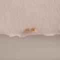 Dainty Topaz Flatback Studs—lightweight gold square earrings, perfect for multiple piercings, shown on a textured beige paper background.