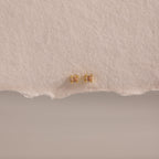 Dainty Topaz Flatback Studs—lightweight gold square earrings, perfect for multiple piercings, shown on a textured beige paper background.