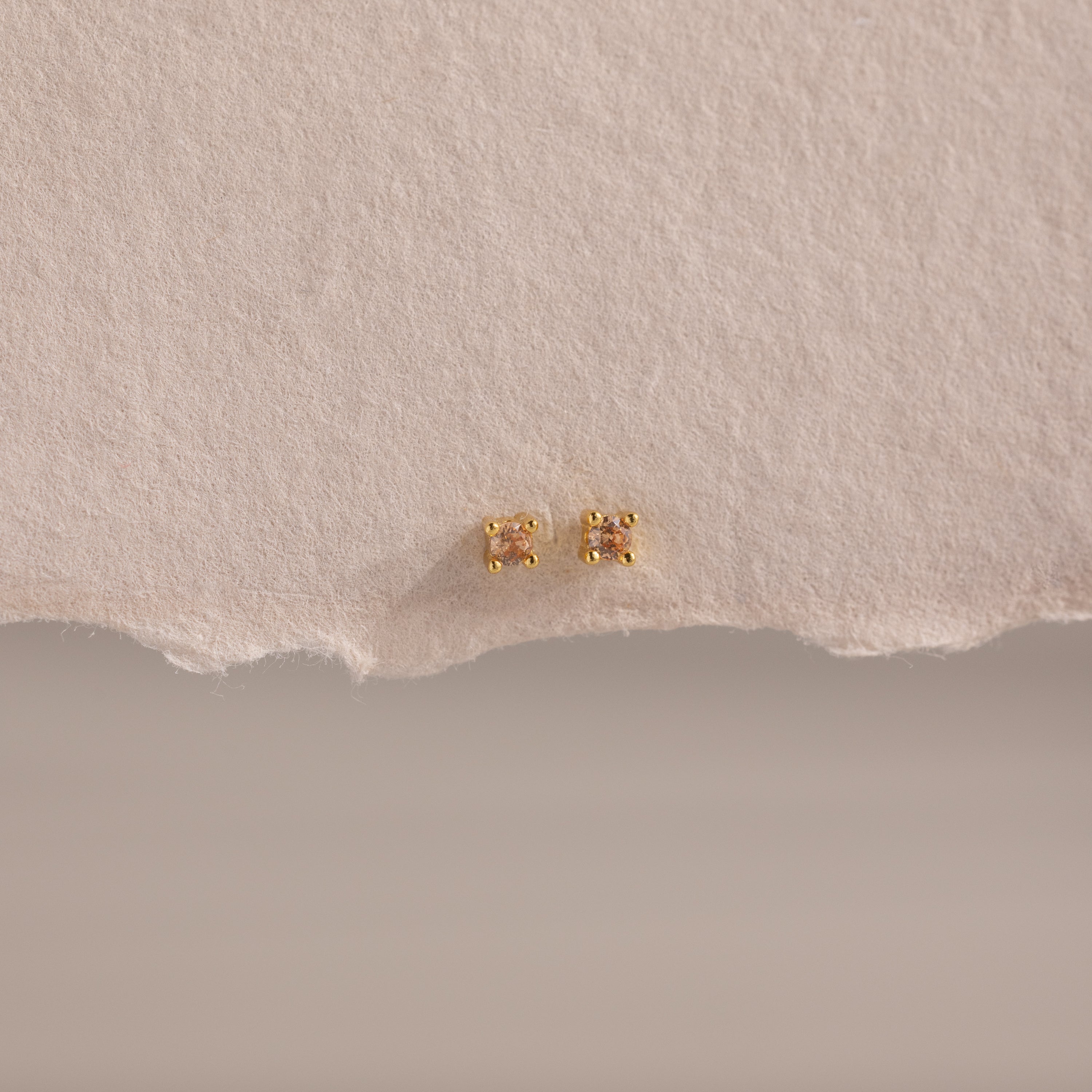 Dainty Topaz Flatback Studs—lightweight gold square earrings, perfect for multiple piercings, shown on a textured beige paper background.