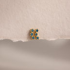 The Blue Zircon Cluster Flatback Studs are displayed on a textured, torn piece of off-white paper.