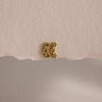 A pair of Peridot Cluster Flatback Studs with green gemstones rests elegantly on a textured, off-white surface.