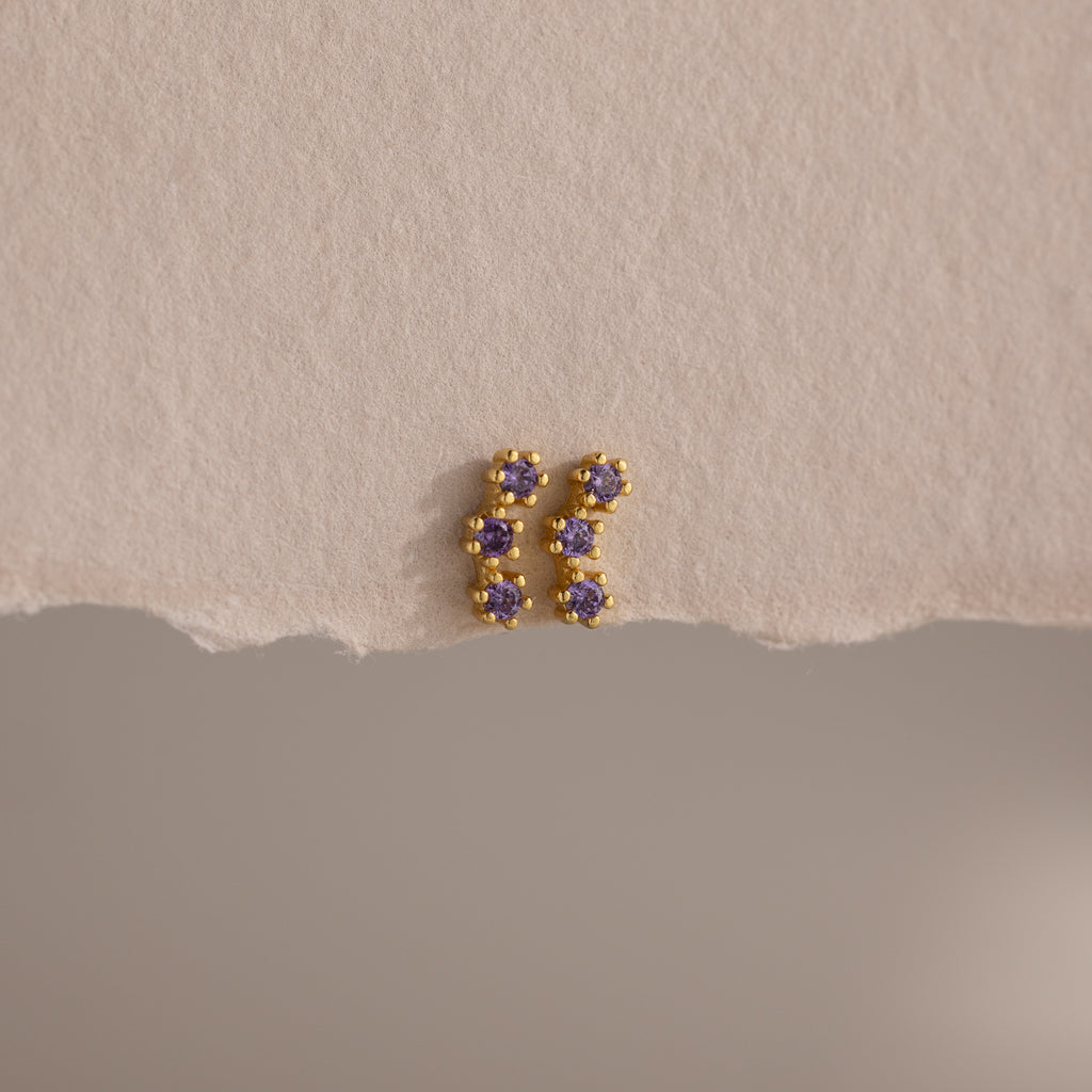 Amethyst Cluster Flatback Studs featuring small purple gemstones are displayed on a textured beige surface.