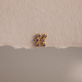 Amethyst Cluster Flatback Studs featuring small purple gemstones are displayed on a textured beige surface.