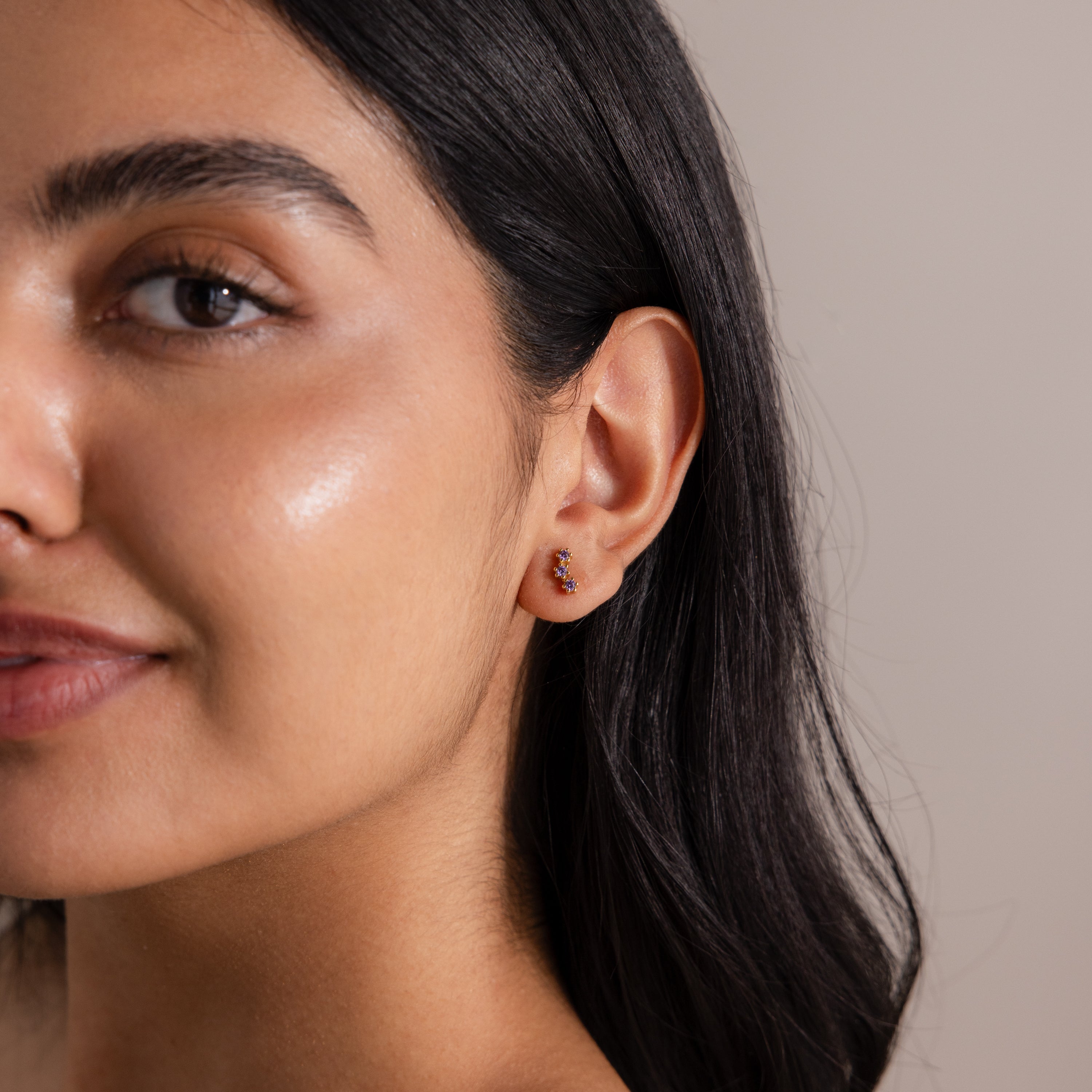 Woman with smooth skin and dark hair wears elegant Amethyst Cluster Flatback Studs, smiling softly.