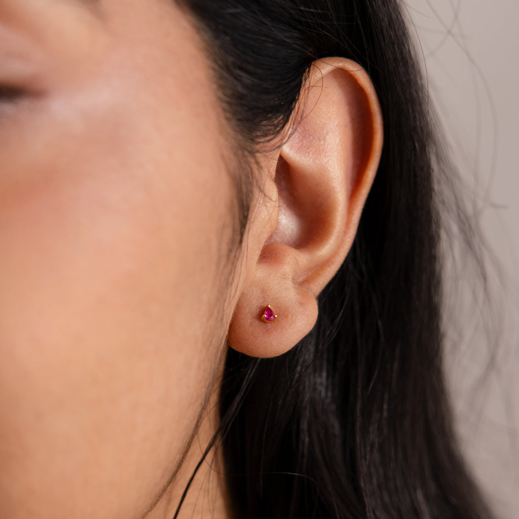 Close-up of an ear wearing Teardrop Pink Tourmaline Flatback Studs, with long dark hair partially visible.