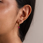 Close-up of a woman's ear wearing Teardrop Birthstone Flatback Studs featuring pink gemstones and a gold hoop—ideal for those who appreciate elegant Birthstone Jewelry.