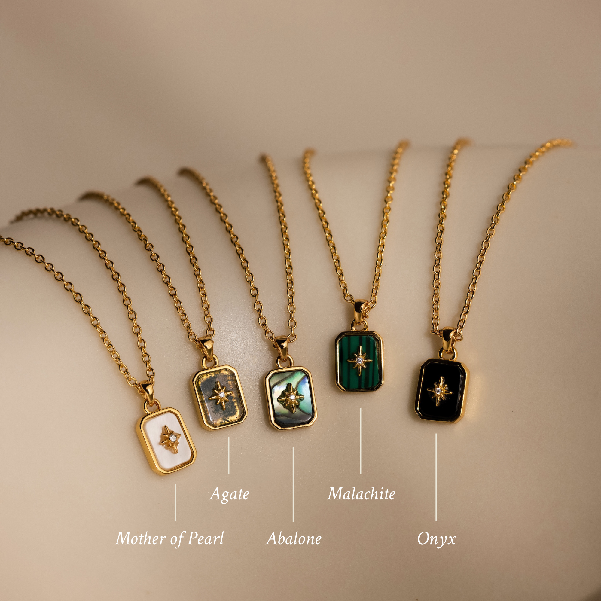 A row of necklaces featuring various designs, including a crystal pendant and the North Star Gemstone Necklace in 18K Gold.