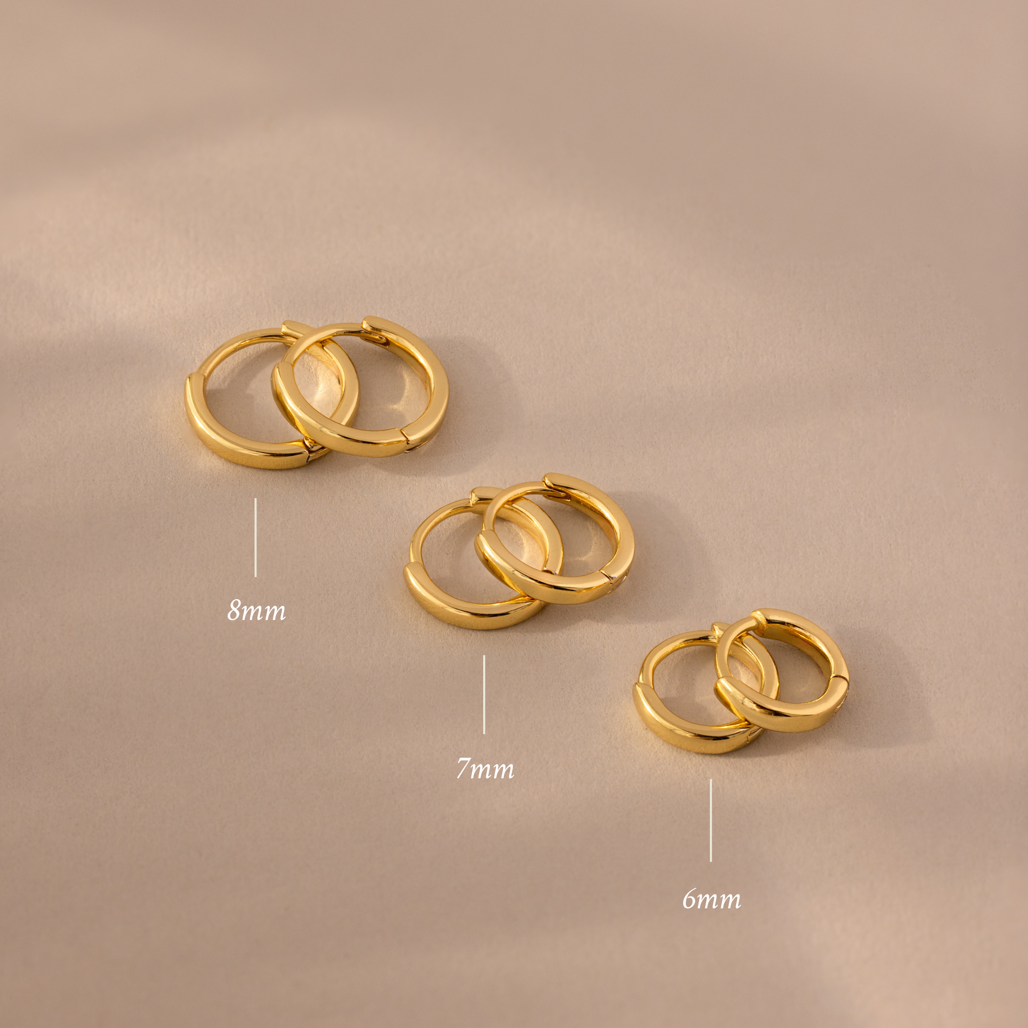 The Dainty Huggies Set features three pairs of gold hoop earrings in 8mm, 7mm, and 6mm sizes—ideal minimalist earrings for your collection.