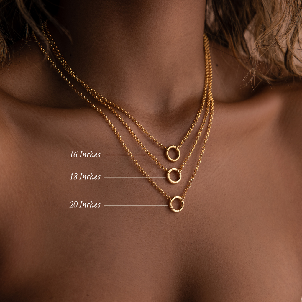The Rolo Circle Charm Necklace is shown layered in 16", 18", and 20" lengths on a woman's neck, highlighting a minimalist style with classic rolo link chains.