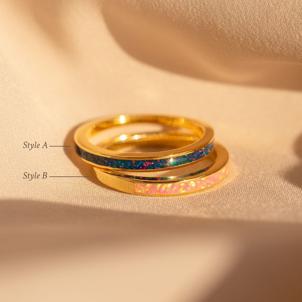 The Opal Inlay Rings Set rests on beige fabric: one ring features an indigo blue inlay, while the other showcases a Pink Flamingo inlay.