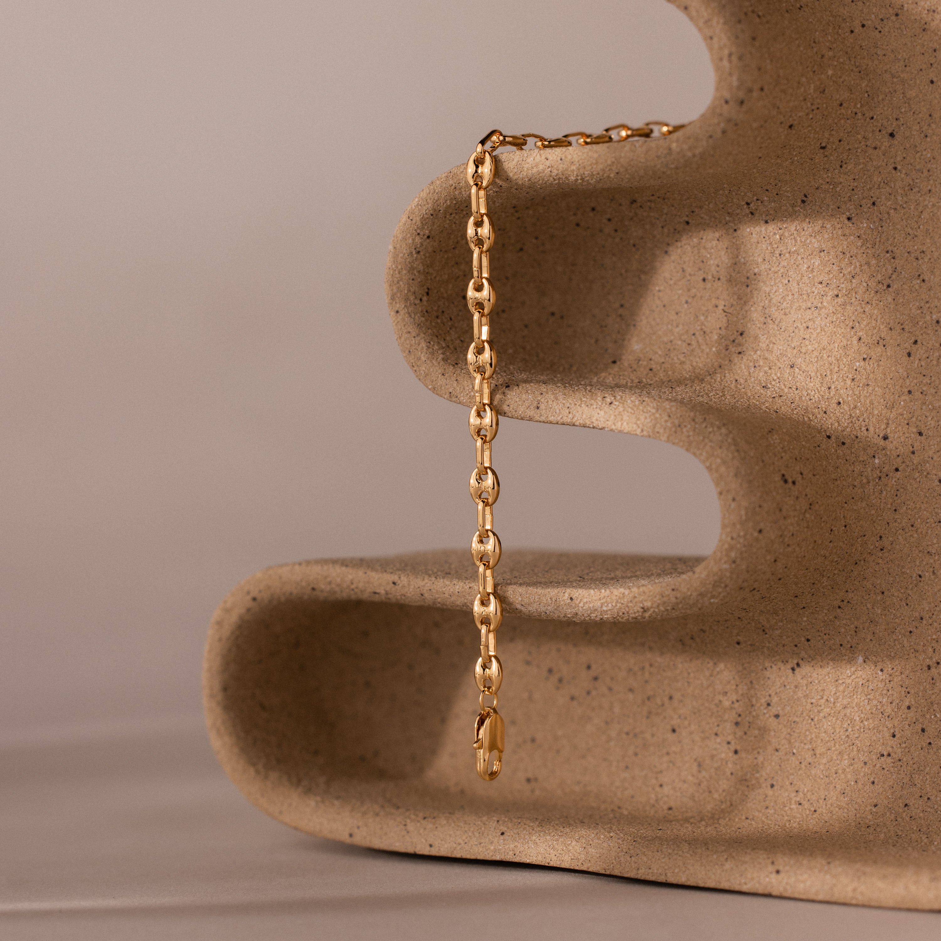 Mini Mariner Chain Bracelet in gold, draped over a sculptural stone display.