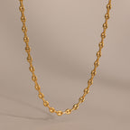 Gold mariner chain necklace with polished oval links, displayed against a neutral beige background.