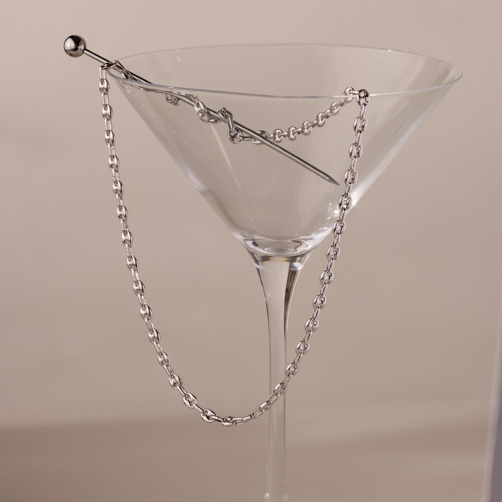 Silver mariner chain necklace with polished oval links, elegantly draped over the rim of a clear martini glass with a silver stir stick.