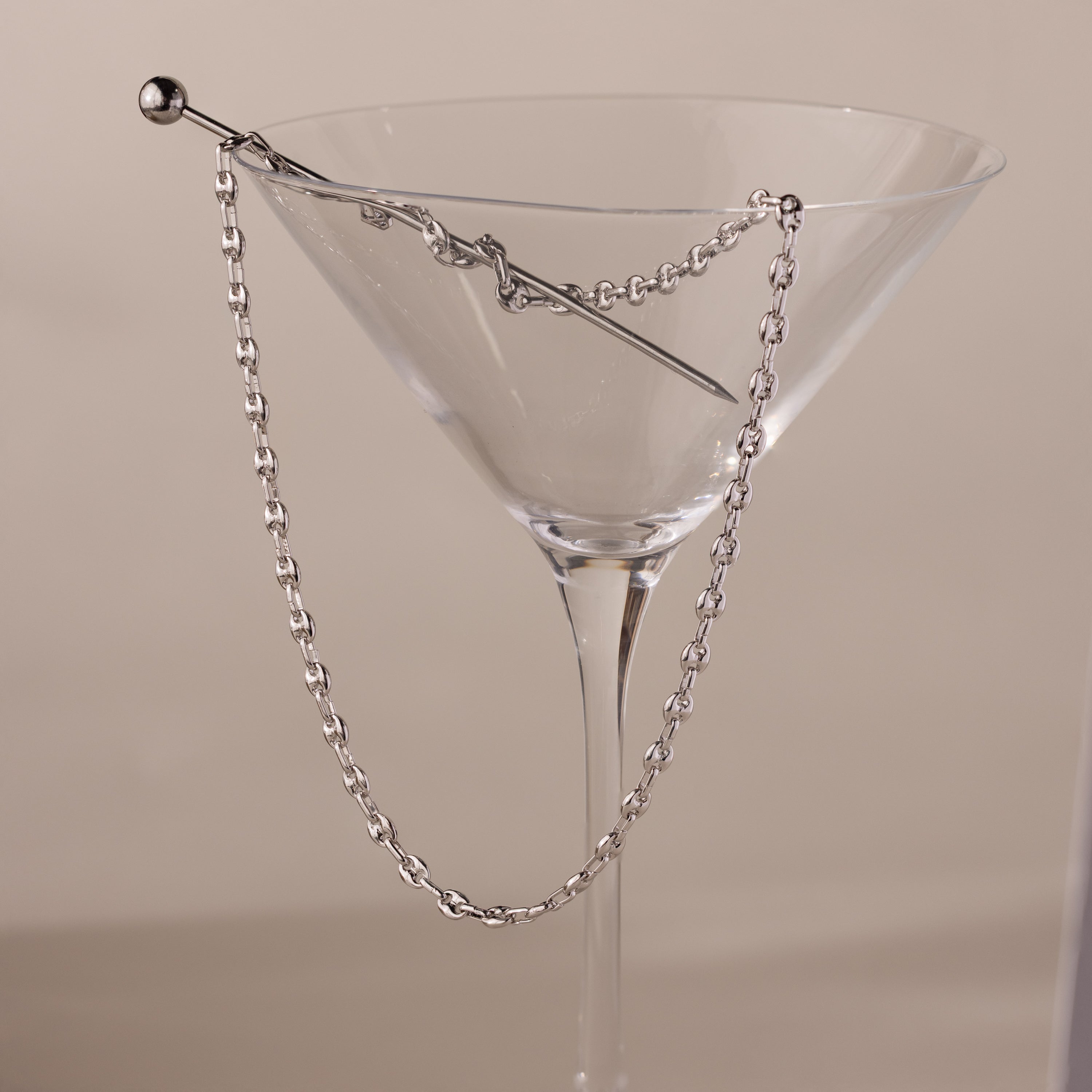 Silver mariner chain necklace with polished oval links, elegantly draped over the rim of a clear martini glass with a silver stir stick.