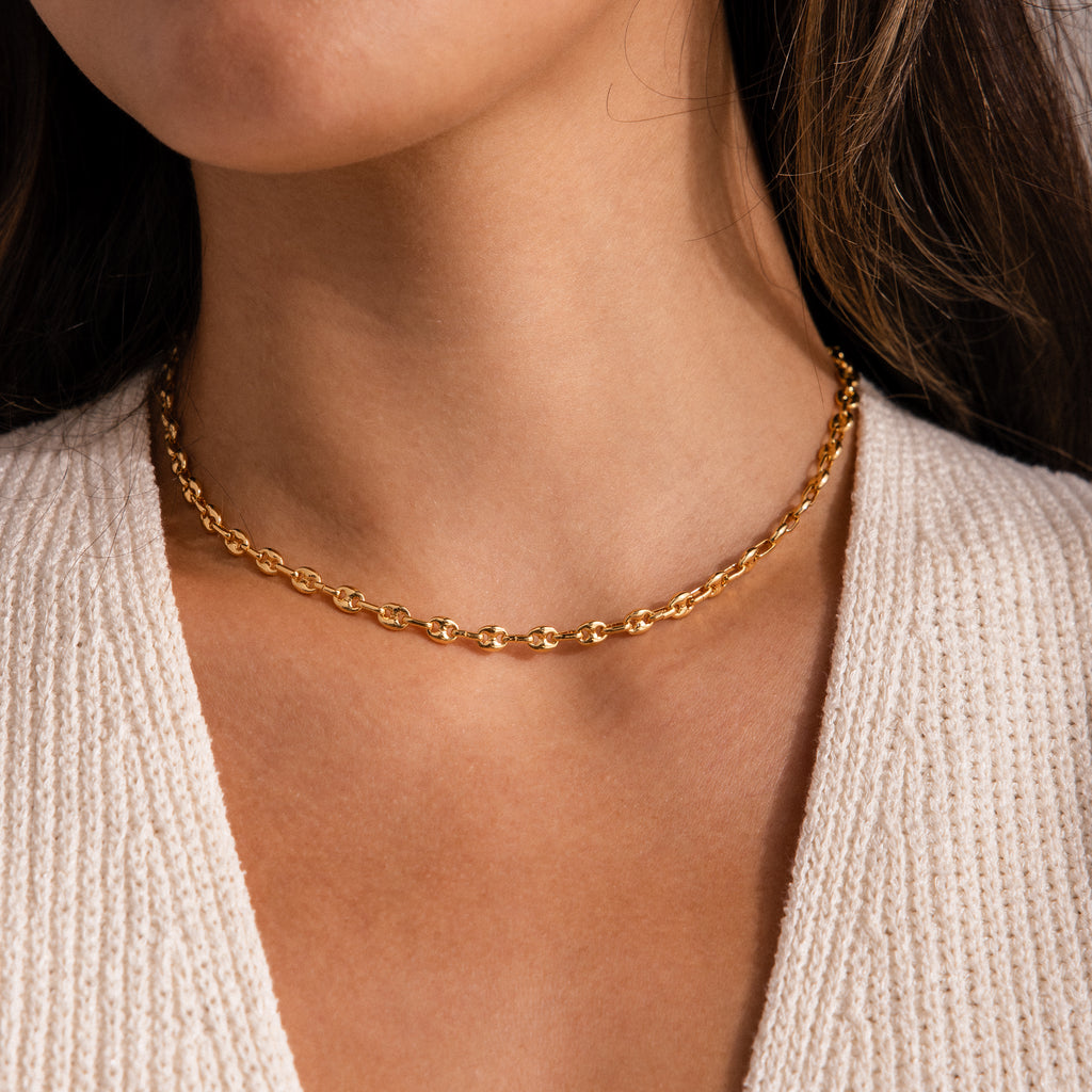 Model wearing a gold mariner chain necklace with polished oval links, styled as a choker.