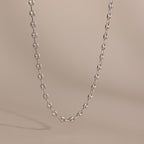 Silver mariner chain necklace with polished oval links, displayed against a neutral beige background.
