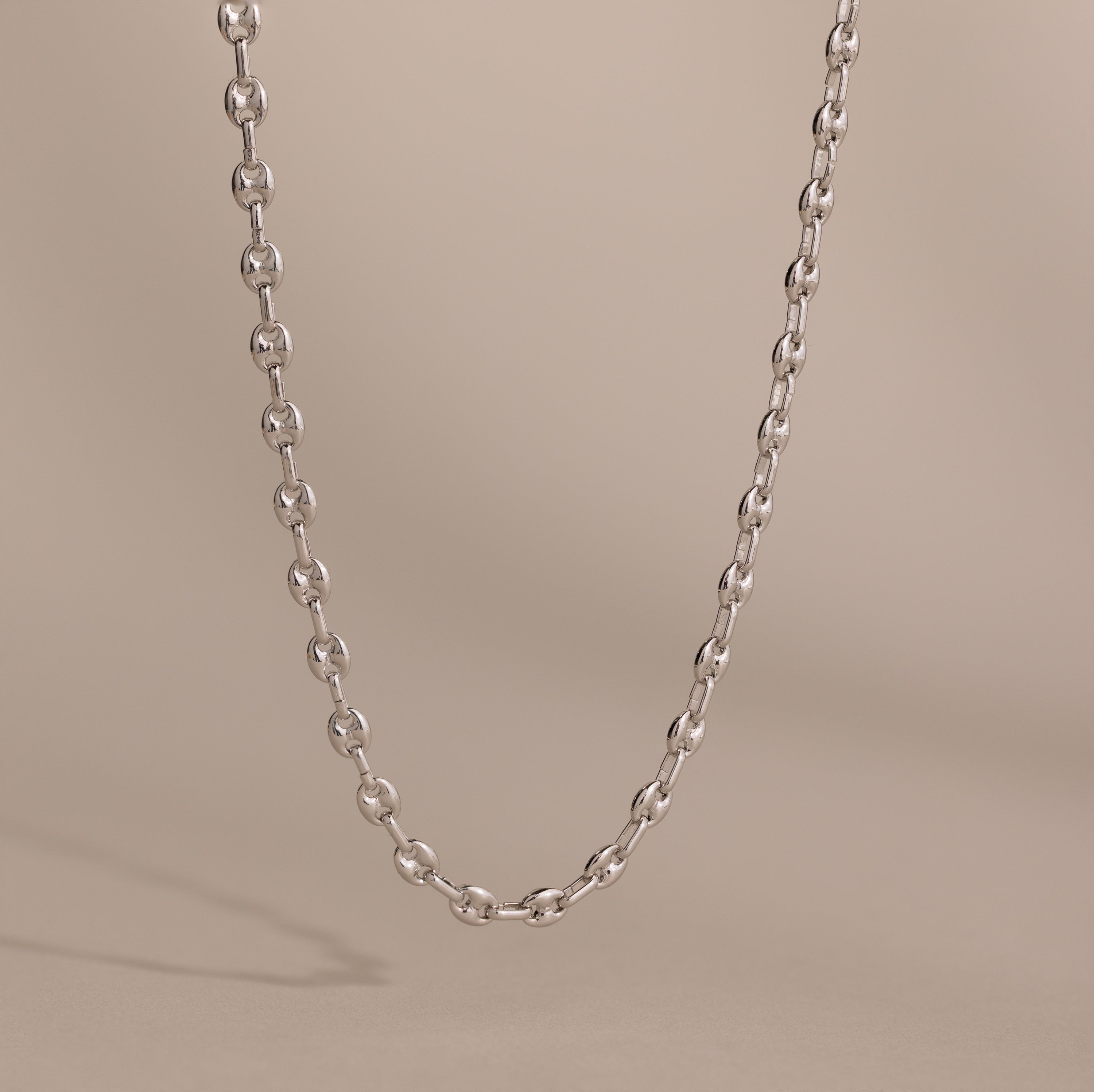 Silver mariner chain necklace with polished oval links, displayed against a neutral beige background.