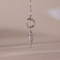 Silver fish charm pendant with intricate scale detailing, hanging from a polished circular link on a chain.