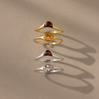 The Sculpted Toi et Moi Ring Set features four gold and silver rings with teardrop-shaped stones, ideal for stacking or making a statement. Their delicate design casts soft shadows on beige, enhancing any look.