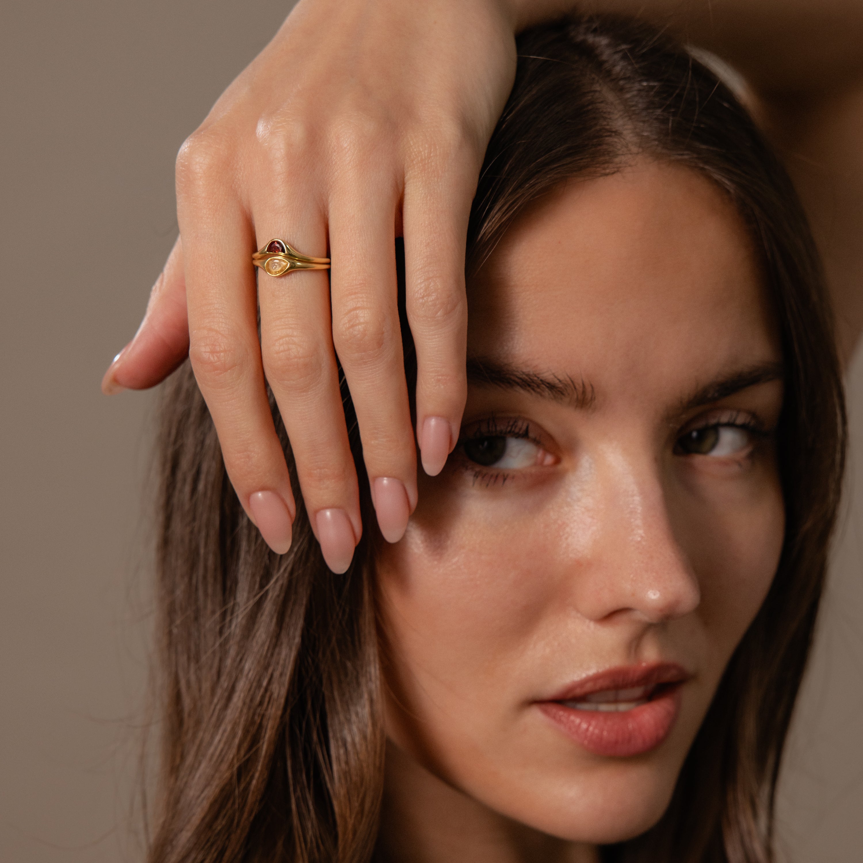 A woman with long hair touches her face, showcasing the Sculpted Toi et Moi Ring Set on her finger.