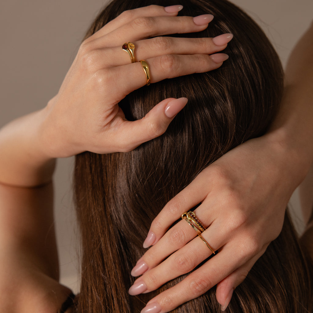 A woman with manicured nails showcases her hands, adorned with the Sculpted Toi et Moi Ring Set in Silver and gold rings, against a backdrop of brown hair.