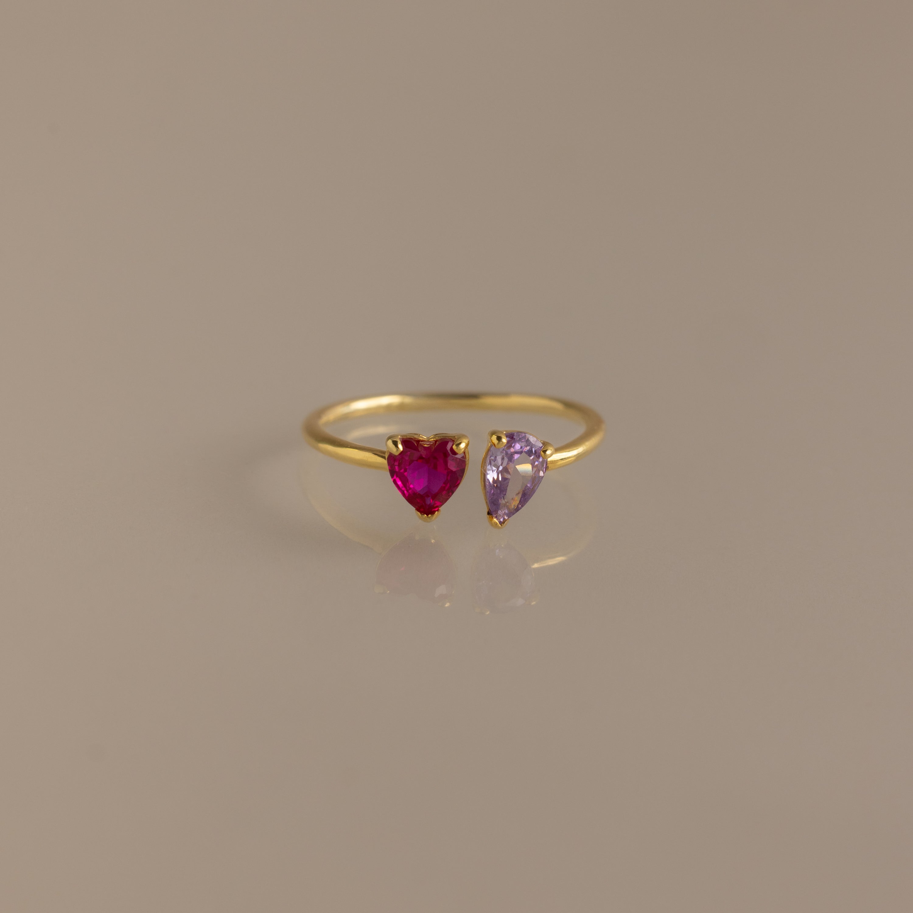 Love Toi et Moi Ring in 18K Gold with a red heart-shaped gemstone and a purple heart-shaped gemstone, shown on a beige background—a romantic stacking ring.